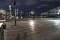 a view of new york city skyline at night from pier on the hudson river side