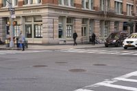 the person is crossing the street at this crosswalk intersection to get there car to be seen