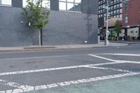 a paved road with a stop light at an intersection near a building with an arrow painted on it