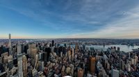 the cityscape of new york is bathed by a sun light below it, the skyscrapers have very large windows