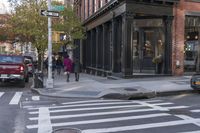 a crosswalk has two people walking across it on the street with several cars on both sides of it