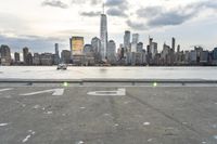 empty parking lot with new york skyline in background as seen from water edge in cloudy day