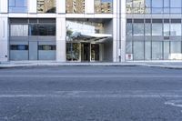 an entrance into a glass building and street scene on a gray day with blue sky and clouds