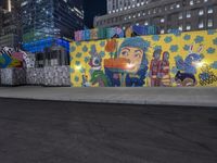 street with large graffiti wall along the side of it near a city street with buildings