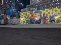 street with large graffiti wall along the side of it near a city street with buildings