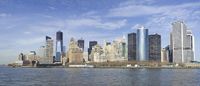 the lower manhattan buildings are on the horizon of a city lake with boats passing by