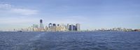 the lower manhattan buildings are on the horizon of a city lake with boats passing by