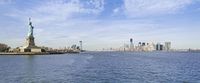 the lower manhattan buildings are on the horizon of a city lake with boats passing by