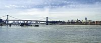 the lower manhattan buildings are on the horizon of a city lake with boats passing by