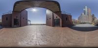 a wide angle of a mirror that shows the building in front of it and person on a bicycle