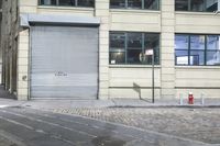 a fire hydrant in front of a long metal door on the corner of a city street