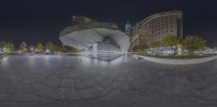 a 360 - up photo shows an abstract building near the sidewalk at night in the city