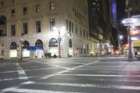 an intersection with white painted crosswalk and buildings in the background at night time and one street light on