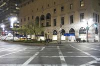 an intersection with white painted crosswalk and buildings in the background at night time and one street light on