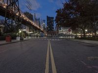 an empty road on a city street near the water at night, with streetlights glowing down