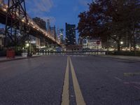 an empty road on a city street near the water at night, with streetlights glowing down