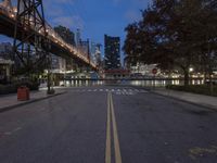 an empty road on a city street near the water at night, with streetlights glowing down