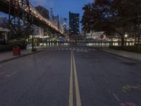 an empty road on a city street near the water at night, with streetlights glowing down