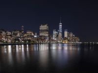 the city skyline of a large city is lit up at night as the boat travels down the water