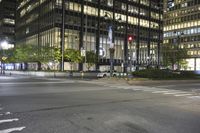 a cross walk and road in front of an office building at night with lights on