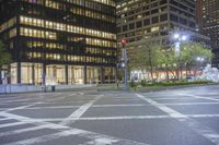 a cross walk and road in front of an office building at night with lights on