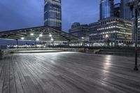 a view of new york city skyline at night from pier on the hudson river side
