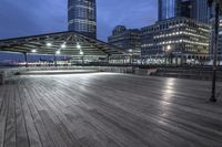 a view of new york city skyline at night from pier on the hudson river side