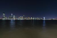 the city skyline from the shore of the water at night, as seen from across the bay