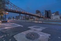 an empty road has fallen leaves and some lights on a bridge in the background in downtown pittsburgh