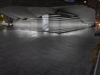 an empty open air hallway with a tiled floor, and large, vertical panels of lights