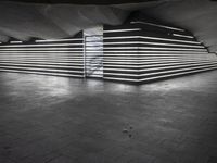 an empty open air hallway with a tiled floor, and large, vertical panels of lights