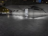 an empty open air hallway with a tiled floor, and large, vertical panels of lights