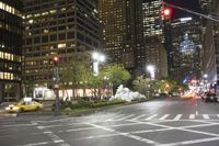 a night view of the busy streets with lots of cars and traffic signals with tall buildings in the background