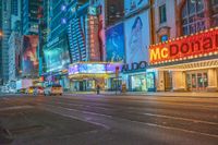 a night time view of buildings and street in the city at night with neon signs that read