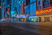 a night time view of buildings and street in the city at night with neon signs that read