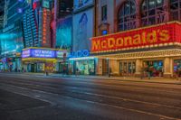 a night time view of buildings and street in the city at night with neon signs that read