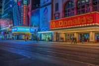 a night time view of buildings and street in the city at night with neon signs that read