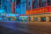 a night time view of buildings and street in the city at night with neon signs that read