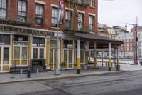 a corner cafe that is on the street side of the town, with chairs, tables and benches in front of it