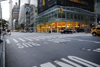 an intersection of buildings with traffic lights and yellow cabs on street, as pedestrians cross the sidewalk