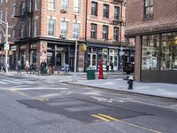 city sidewalk with people walking, traffic lights and a fire hydrant on it and a sign near the street