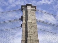 a tall stone tower with people standing on it under the canopy of the bridge above the clouds