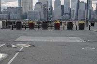 a paved park with benches next to a water body and a skyline of high rises in the background