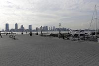some people are sitting at the bench by the water on a bright sunny day in the city