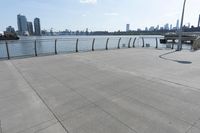 the woman is walking down the sidewalk towards the water next to her bicycle racket