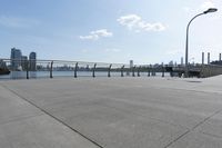 the woman is walking down the sidewalk towards the water next to her bicycle racket