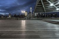 a view of new york city skyline at night from pier on the hudson river side