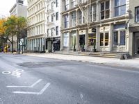 a paved city street with a tall building and two empty bike racks on each side of it