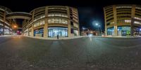 a city street with traffic lights and a store at night time through a fisheye lens