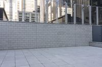 a large gray trash can next to tall buildings on a street near a fence with metal bars around it